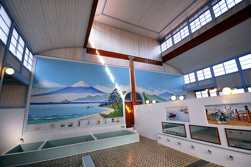 A traditional (non-super) Tokyo sento. Bathers wash at the taps in front of the mirrors, before entering the tubs at the back of the room. The wall on the right divides the men’s and women’s sides